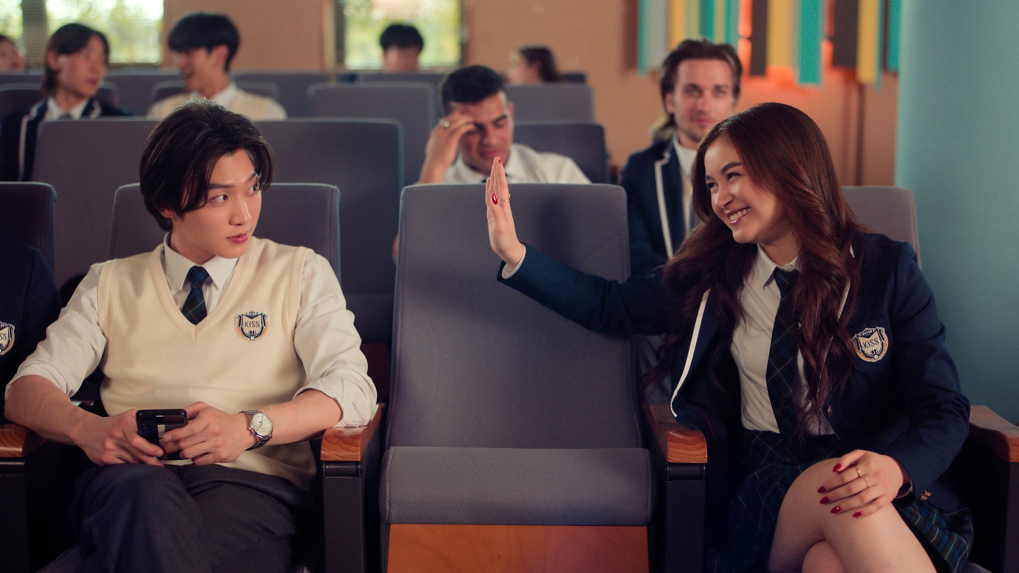 A grinning high school student attempts to high five another, who looks bemused.
