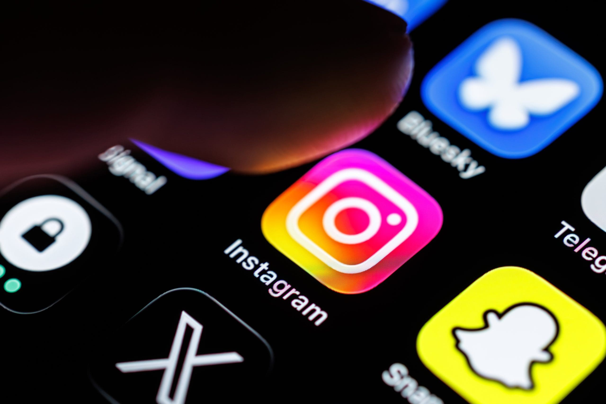 A finger hovering the Instagram app icon on a phone screen.